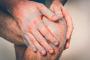 Man with knee pain is holding his aching leg - retro style