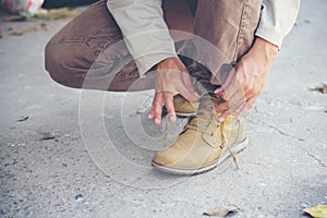 Man kneel down and tie shoes industry boots for worker. Close up shot of man hands tied shoestring for his construction brown