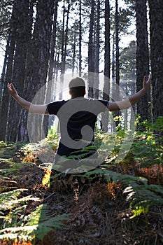 Man Kneeling with Arms Lifted in Forest