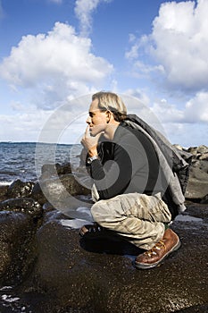 Man kneeling by the coast of Maui, Hawaii.