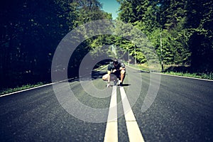 Man kneeling on a country road looking exhausted after jogging