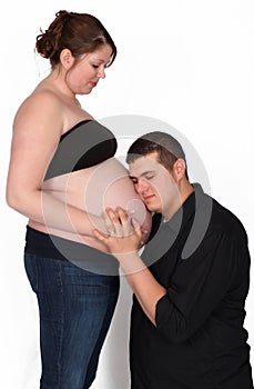 Man kneeling with face on woman's pregnant belly