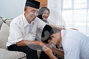 Man kneeling and kiss his parent`s hand asking for forgivness photo