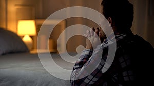 Man kneeling near bed and praying to god, thanking for life opportunities photo