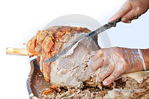 man with knife is cutting slices of the roasted pork
