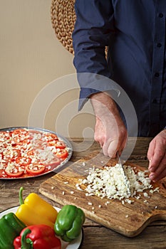 Man knife sliced onion pizza on a cutting board