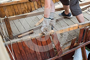 The man knocks an old rotten wooden plank with a hammer