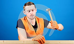 Man, labourer, handyman in bright vest and protective gloves handcrafting, blue background. Handcrafting concept