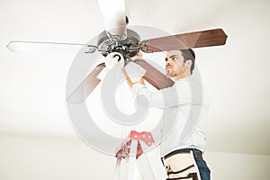 Man in ladder fixing ceiling fan