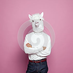 Man with lama head standing with crossed arms on bright pink studio wall background