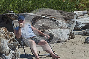 Man laouges in a folding chaise on the beach at Siletz Bay Park, Lincoln City, Oregon