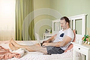 Man with a laptop in bed relaxin while working from home photo