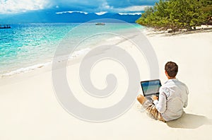 Man with laptop on colorful beach