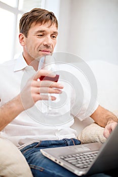 Man with laptop computer and glass of red wine