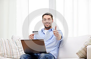 Man with laptop and credit card showing thumbs up