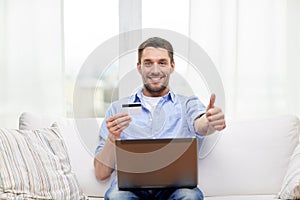 Man with laptop and credit card showing thumbs up