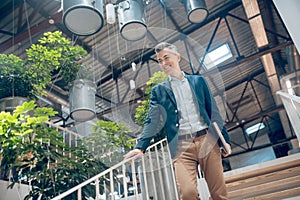 Man with laptop going down stairs indoors