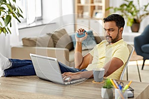 Man with laptop and hand expander at home office