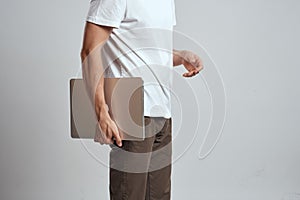 A man with a laptop in his hands on a light background in a white t-shirt emotions light background new technologies