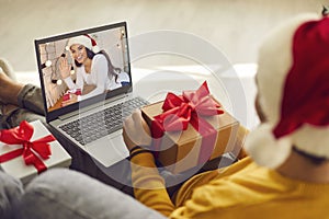 Man with laptop holding present and video calling his girlfriend on Christmas holidays