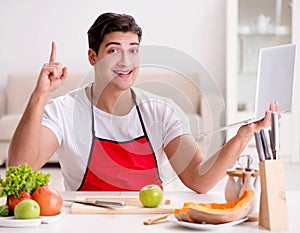 Man with laptop preparing food at the kitchen