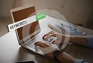 Man with laptop searching for keywords at table