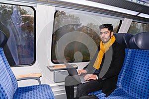 Man with laptop sits near window in train journey