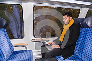 Man with laptop sits near window in train journey