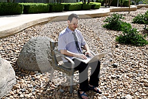 Man with a laptop sits in a rock garden on Ben Gurion University