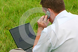 Man with laptop sitting in grass