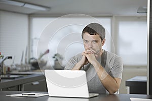 Man With Laptop Sitting At Kitchen Counter