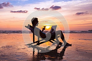 Man with laptop on sunset beach