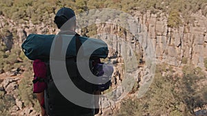 A man with a large backpack and hiking equipment in the mountains.