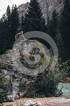 Man on a large stone, a boulder, among the incredibly beautiful river of turquoise color, vertical photo. Dolomites mountains,