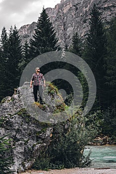 Man on a large stone, a boulder, among the incredibly beautiful river of turquoise color, vertical photo. Dolomites mountains, photo