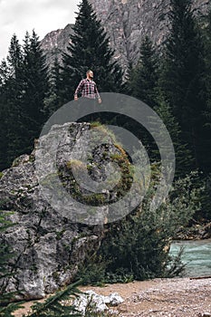 Man on a large stone, a boulder, among the incredibly beautiful river of turquoise color, vertical photo. Dolomites mountains, photo