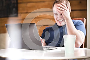 Man laughing while using laptop. Happy smiling guy with computer