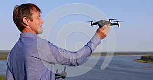 A man launches quadcopter. Flying drone over the river and forest on a sunny day