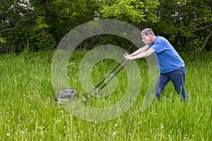 Man with Lawnmower Mowing Tall Grass and Big, Large Lawn