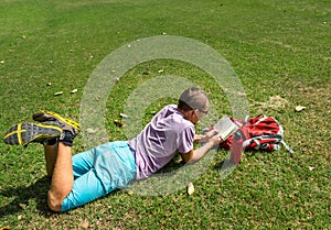 Man laying on the grass and reading his notes