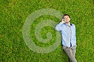 Man laying on a grass talking on a mobile phone