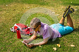 Man laying on the grass and using his tablet