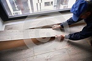 Man laying laminate flooring in apartment under renovation.