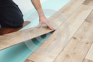 Man laying laminate flooring - closeup on male hands. Worker hands installing timber laminate floor. Easy and quick installation