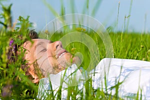 Man laying on a lawn and is dreaming