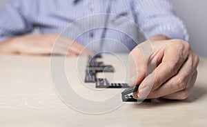 Man laying out dominoes on table. Strategy, business plan drawing up, paving way, planning concept. Hands closeup. Path