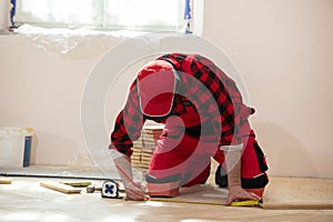 Man laying parquet flooring, worker joining parquet floor. The builder, man is engaged in laying laminate wood floor in the room