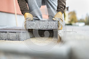 Man laying a paving brick placing it on the sand foundation