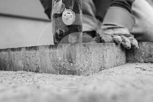 Man laying a paving stone tamping it down with a mallet