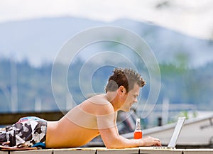 Man laying on pier on laptop